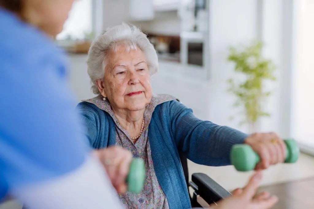 A Movewell clinician guiding an older adult through gentle strength exercises at home